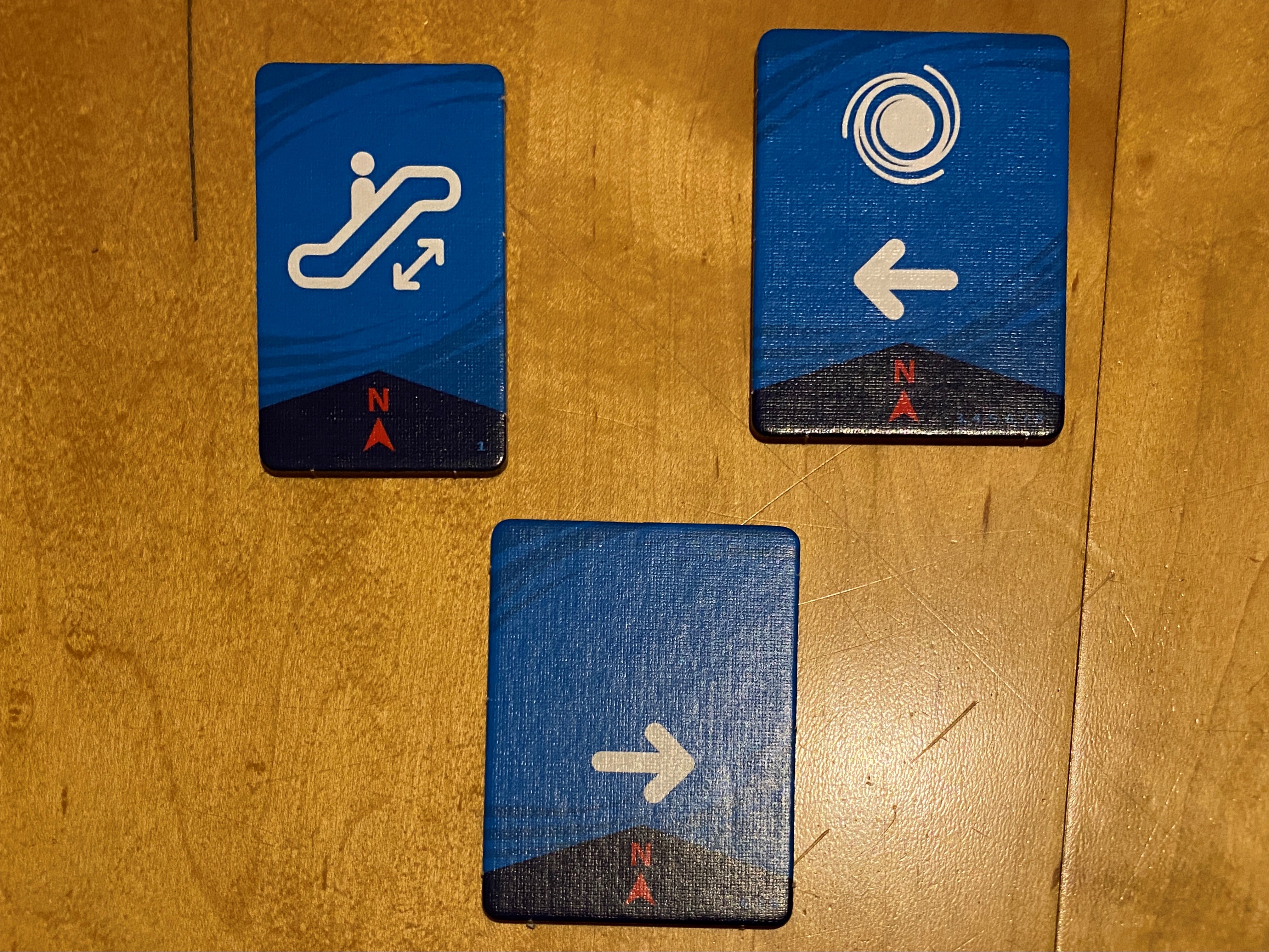 Jeder Spieler erhält eine Karte, die ihm ein bis zwei Fähigkeiten gibt, die er für jeden Helden nutzen kann. Die Karte links oben erlaubt es einem Spieler z.B., die Helden über Rolltreppen zu schicken und der Besitzer der unteren Karte kann die Helden nach rechts bewegen.